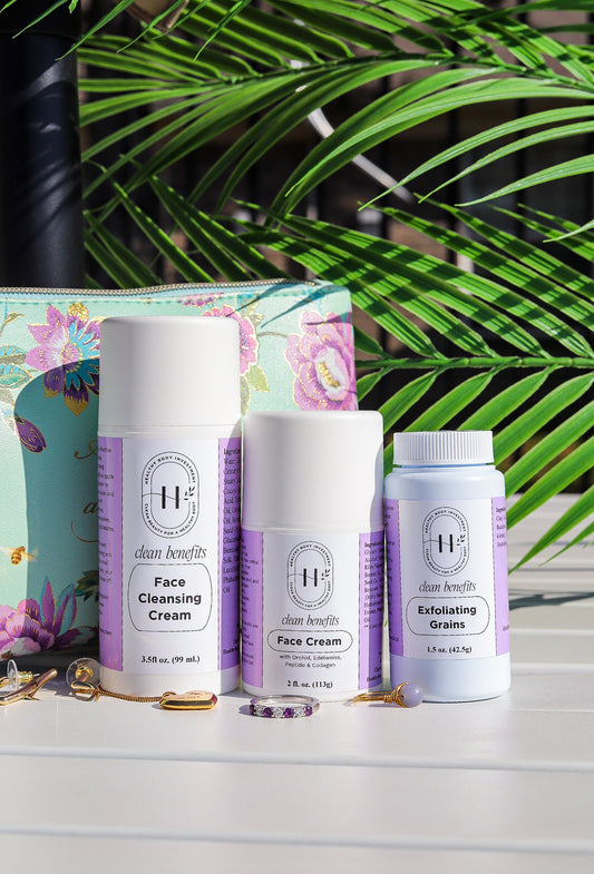 A set of skincare products including a face cream, face cleanser, and exfoliating grains from Clean Benefits. The products are displayed in white bottles and containers, with the face cream and cleanser labeled 'Dr.