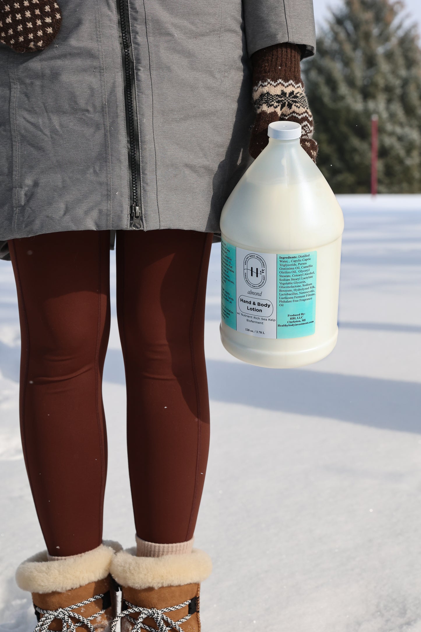 Person holding a large bottle of cleaning solution in a snowy outdoor setting